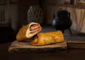 Barra preñada partida, con el chorizo del relleno a la vista, sobre una tabla de madera