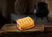 Empanada individual de hojaldre, dorada, sobre una tabla de madera