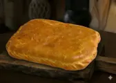 Hornazo pequeño cuadrado de Salamanca, de masa dorada, sobre una tabla de madera